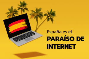 Un ordenador con la bandera de España rodeado de palmeras en un paraíso